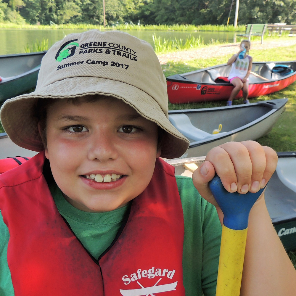 child with hat and canoe